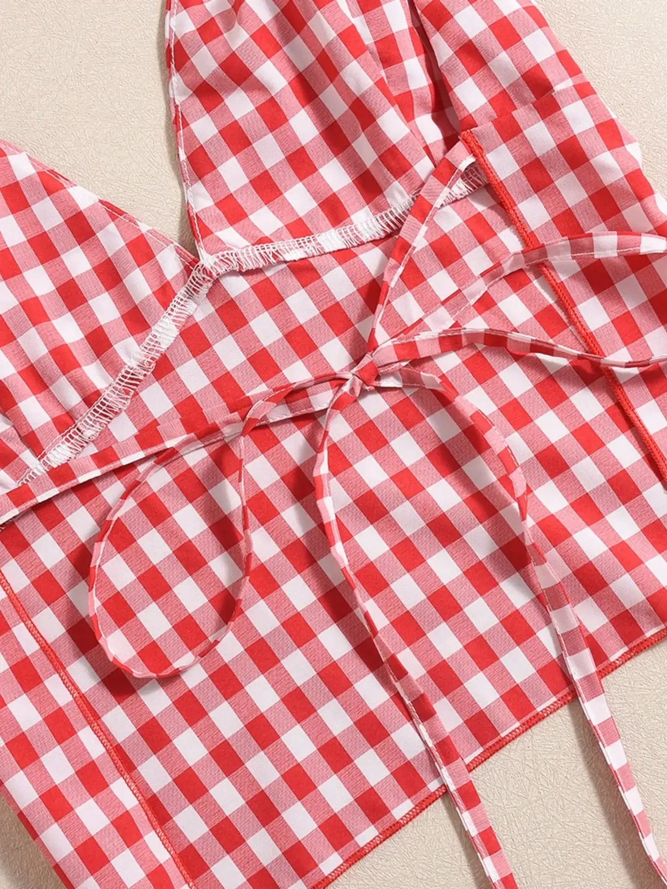 Close-up of red and white plaid halter neck fabric with tied straps from two-piece cami and shorts set.