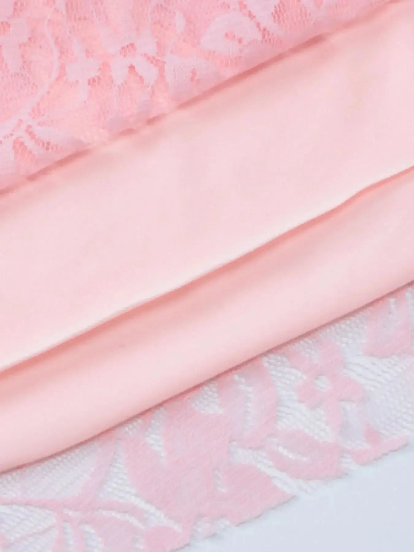 Close-up of soft pink lace and satin fabric, showcasing a delicate texture ideal for a stylish dress.