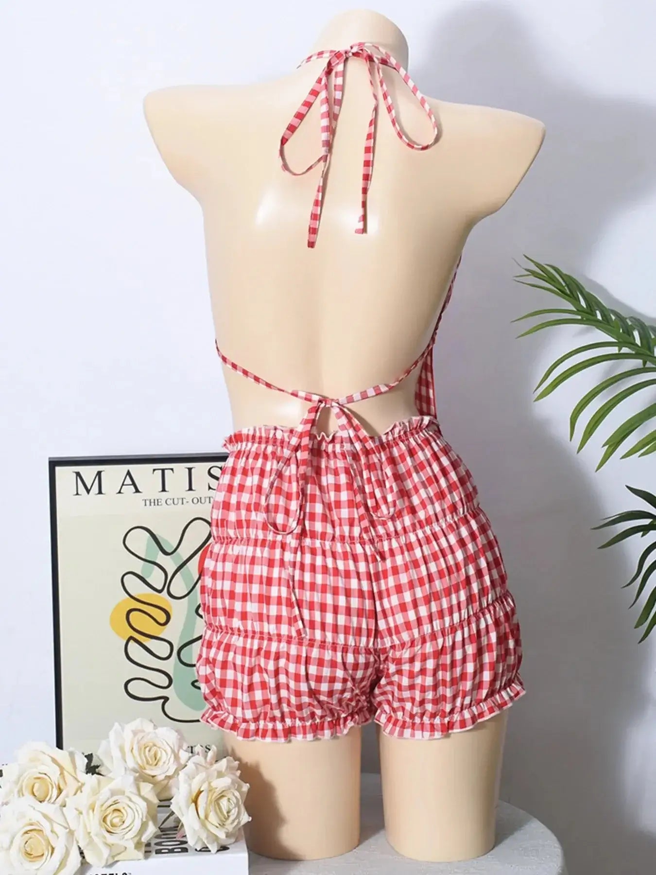 Back view of a plaid halter neck cami and shorts set in red and white, featuring a tied design and ruched details.
