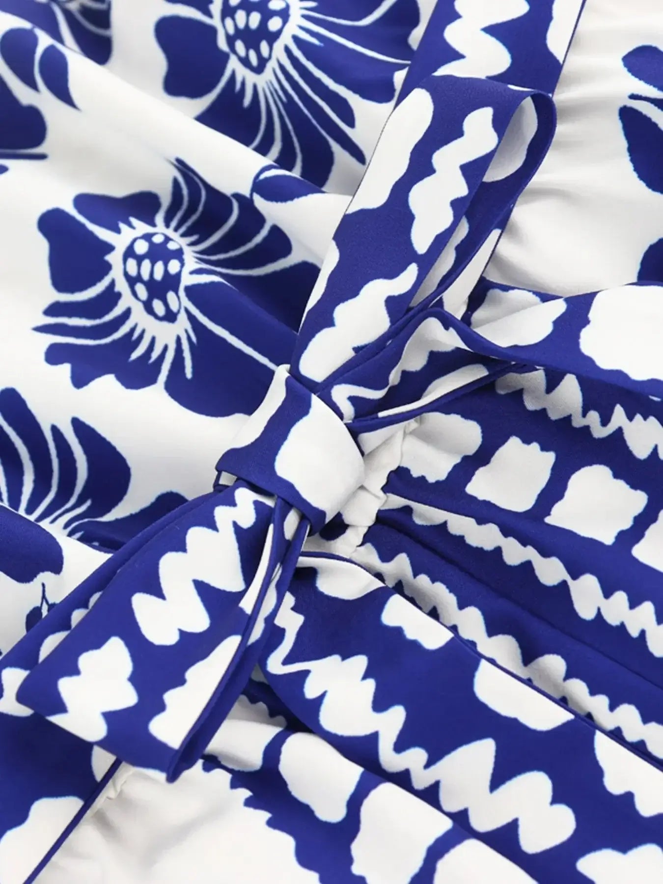 Close-up of a printed tube tie waist romper with blue floral design and belt detail.