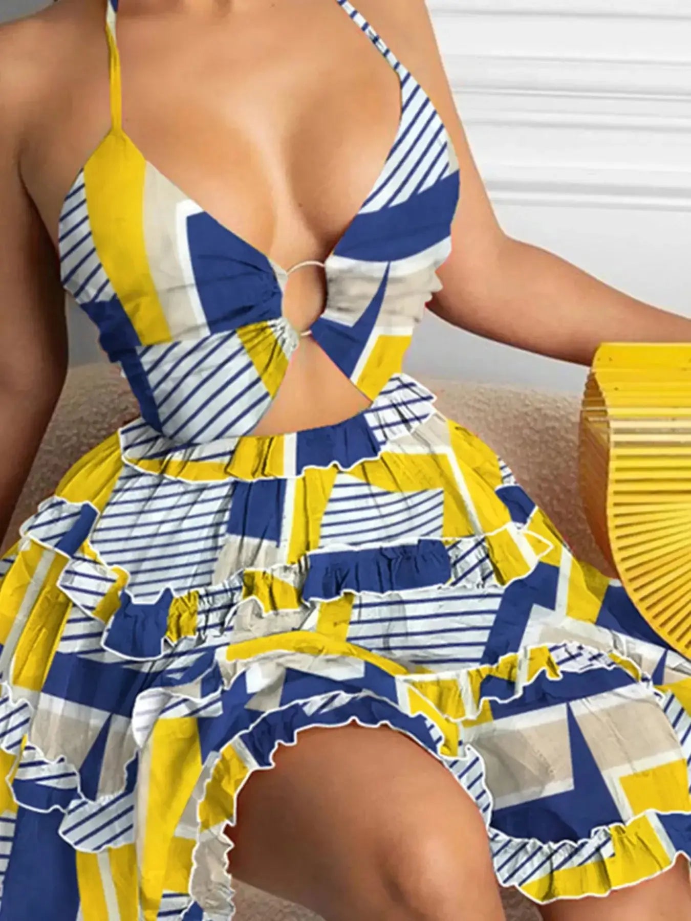 Plus size halter neck cami dress featuring cutout design, ruffles, and vibrant blue and yellow geometric patterns.
