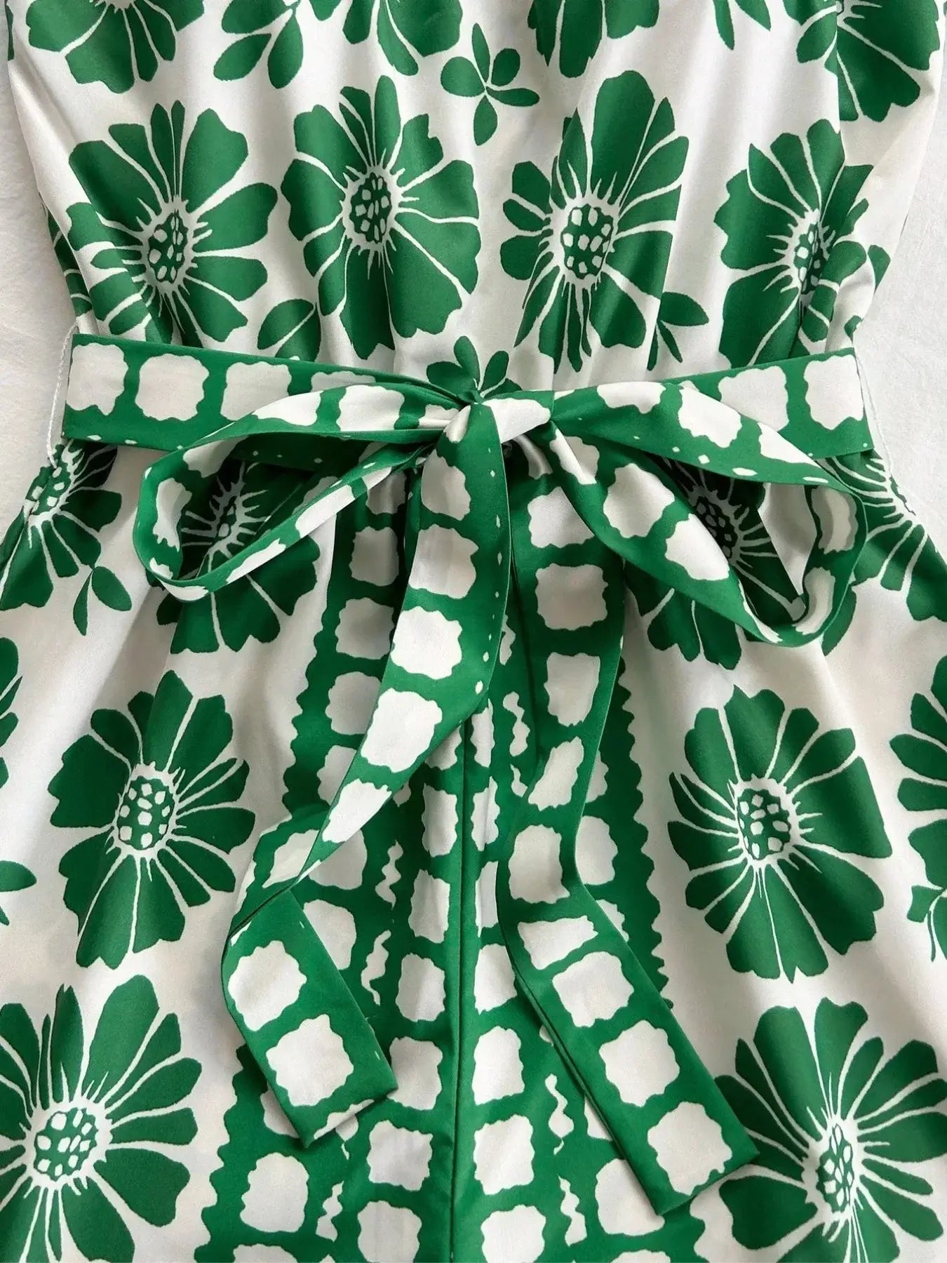 Close-up of the Printed Tube Tie Waist Romper featuring bold green floral patterns and a belted waist for a stylish look.